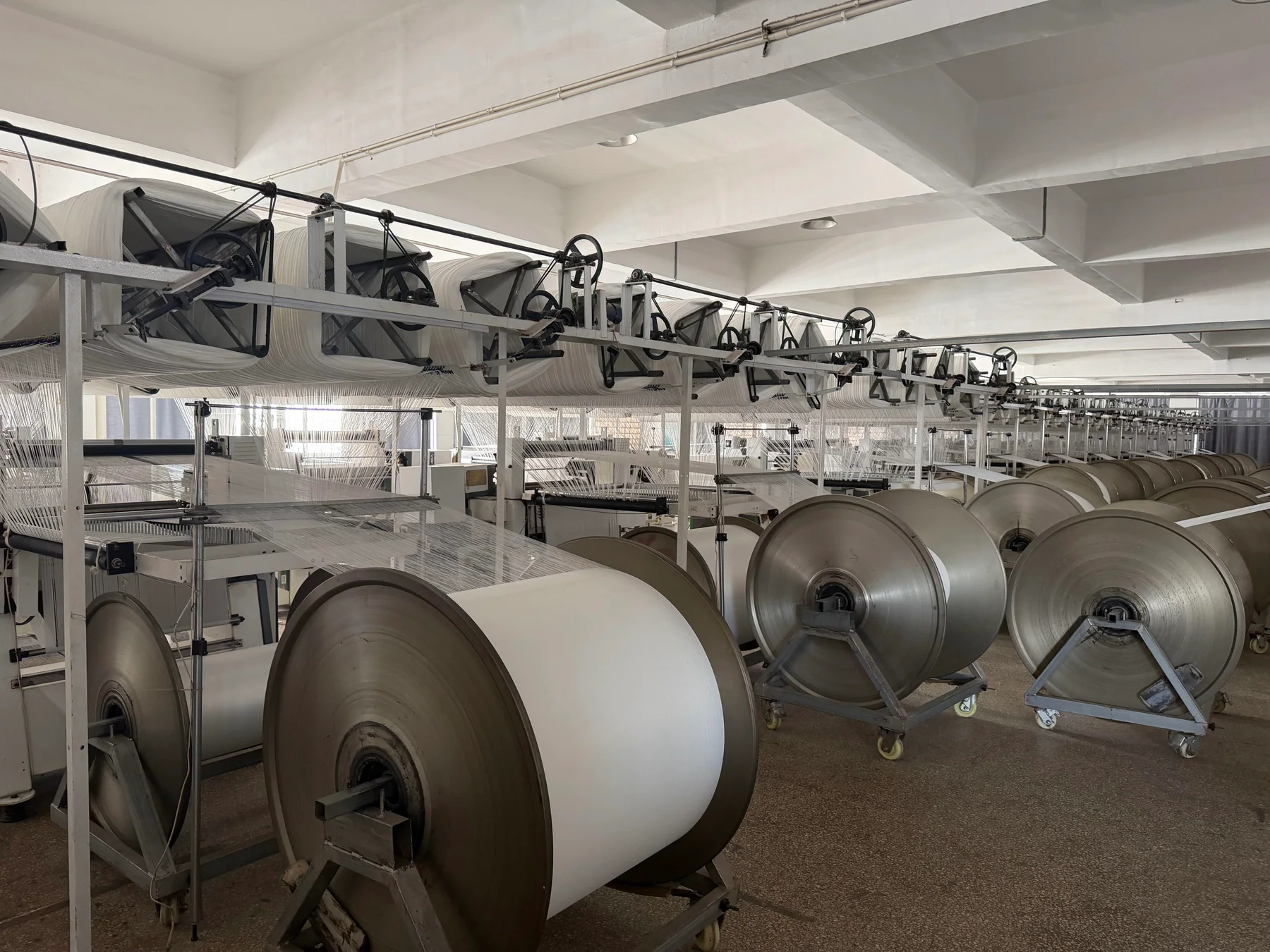 Wide view of textile weaving equipment and yarn beams in the Danli factory workshop