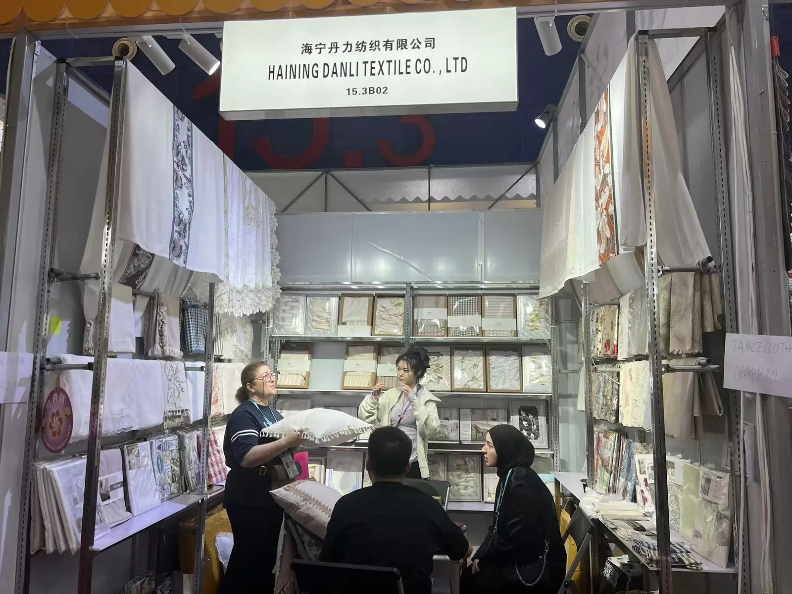 Visitors reviewing a cushion and home textile sample at the Danli booth
